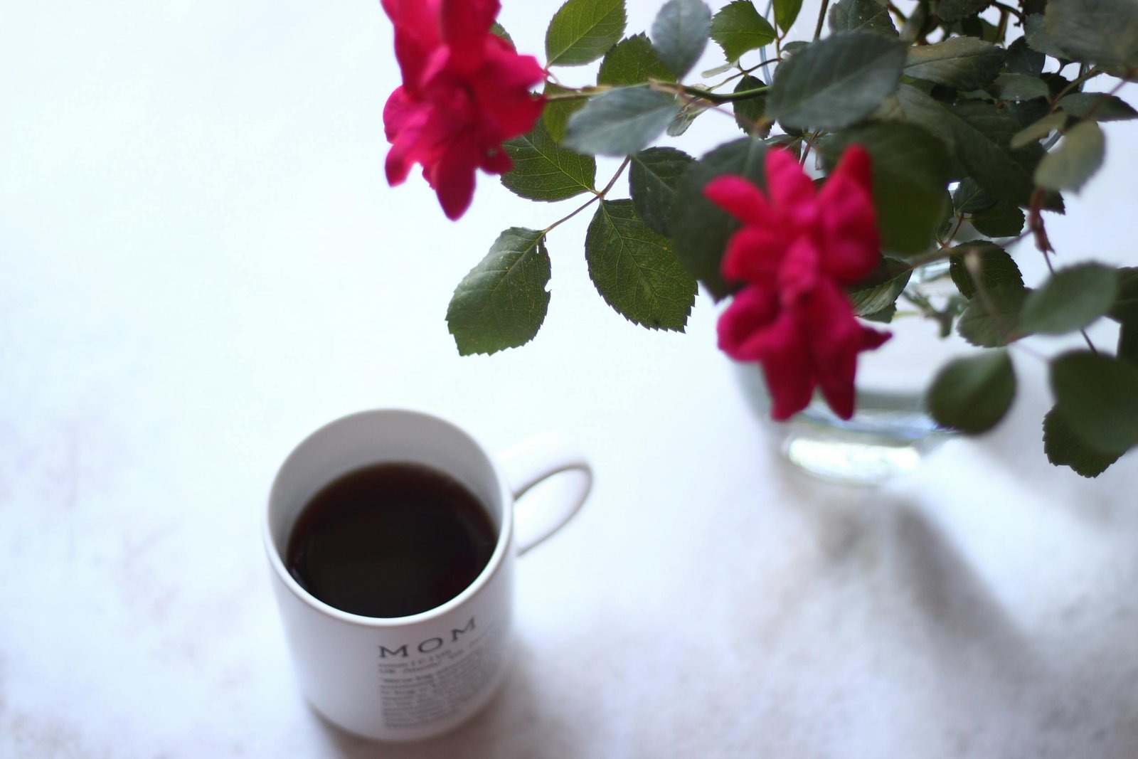 A coffee cup beside vibrant roses, perfect for serene moments and relaxation.